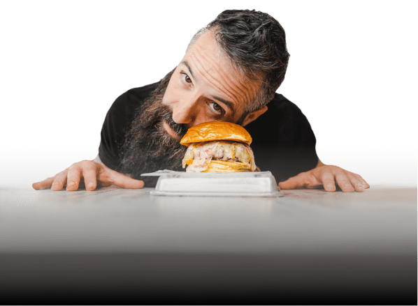 Joe Burger pasándose una hamburguesa por el moflete